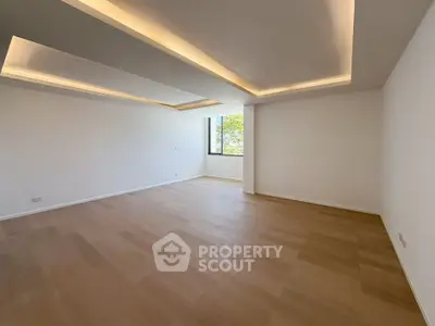 Spacious empty living room with modern ceiling lights and large window view.