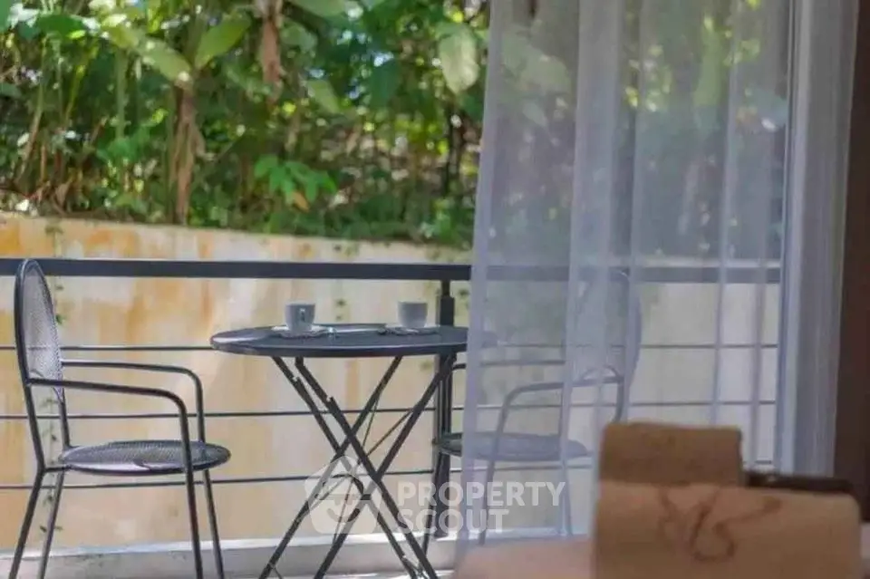 Charming balcony with cozy seating and lush greenery view, perfect for relaxation.