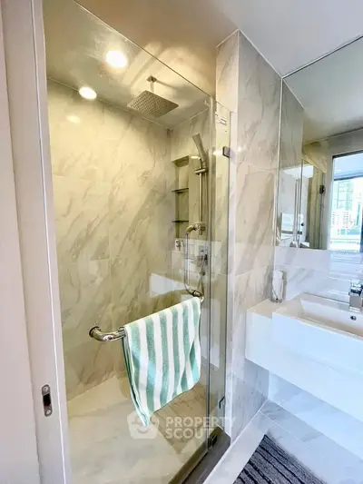 Modern bathroom with glass shower and sleek fixtures in luxury apartment.