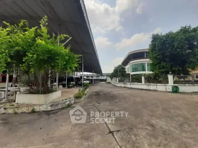 Spacious industrial property with large covered area and lush greenery.
