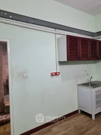 Compact kitchen area with sink and storage cabinets in a cozy apartment.