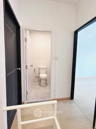 Compact apartment hallway with view into a small bathroom and adjacent room.