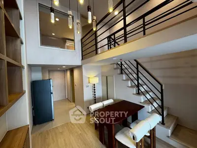Modern duplex apartment with stylish lighting and open layout, featuring a sleek staircase and dining area.