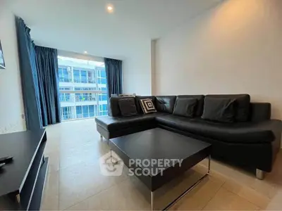 Modern living room with sleek black sofa and large windows offering a bright, airy ambiance.