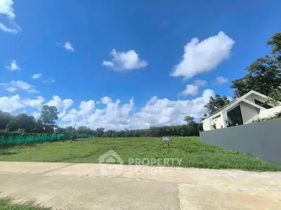 Spacious land plot with clear blue sky, ideal for building a dream home in a serene neighborhood.