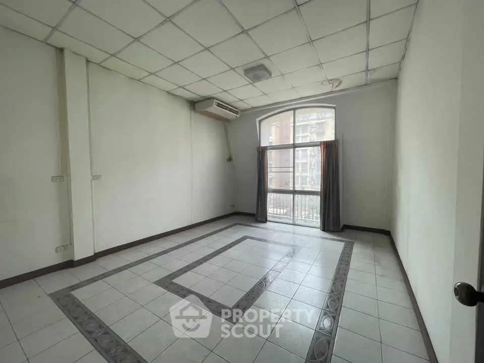 Spacious unfurnished room with large window and tiled floor in modern apartment.