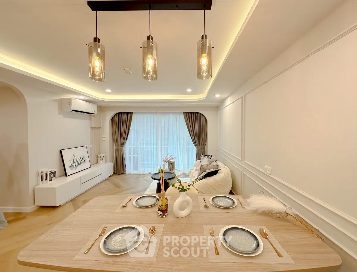 Elegant dining area with modern lighting and cozy living room view