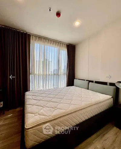 Spacious bedroom with large windows and natural light in modern apartment.