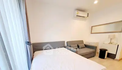 Modern bedroom with cozy sofa and air conditioning, featuring minimalist decor and natural light.