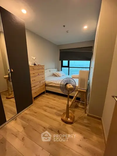 Cozy bedroom with wooden flooring and modern furnishings in a stylish apartment.