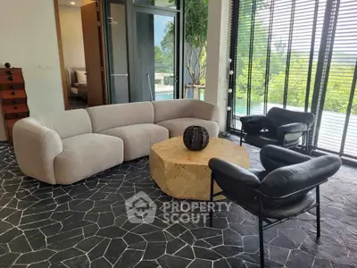 Modern living room with stylish furniture and large windows offering lush garden views.