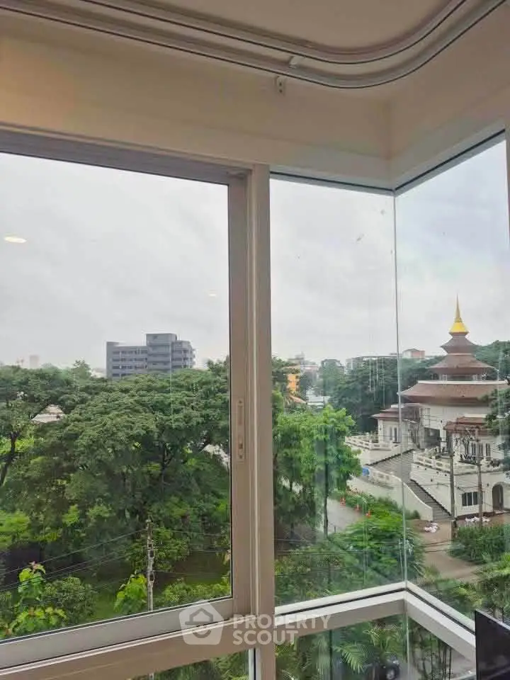 Stunning corner unit with panoramic views of lush greenery and cityscape, featuring large windows for natural light.