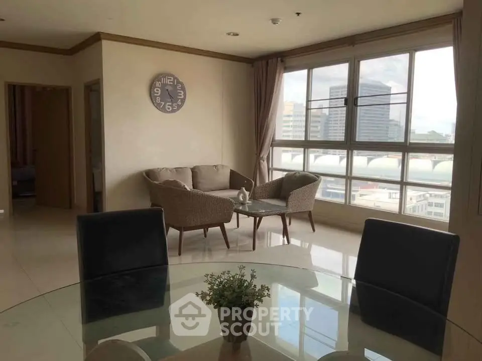 Spacious living room with large windows and city view, featuring modern furniture and elegant decor.
