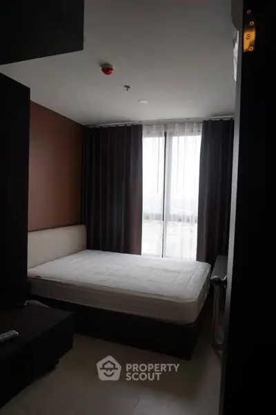 Cozy bedroom with large window and modern furnishings in a stylish apartment.