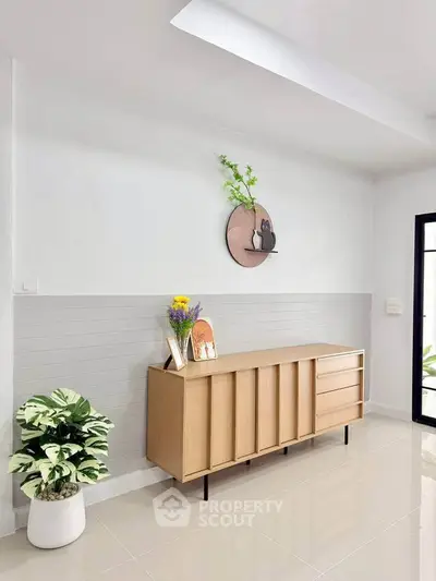 Modern minimalist interior with sleek wooden sideboard and decorative wall art in bright living space.