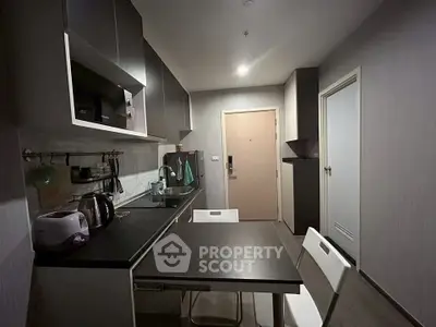 Modern compact kitchen with sleek cabinetry and dining area in a cozy apartment.