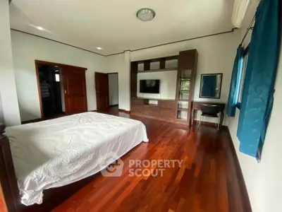 Spacious bedroom with wooden flooring and built-in wardrobe in modern home