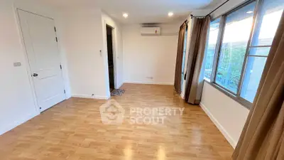 Spacious empty room with wooden flooring and large windows, perfect for customization.