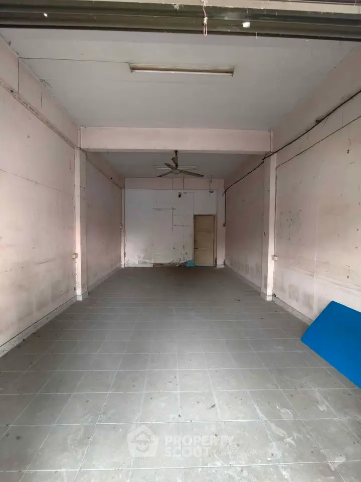 Spacious empty room with tiled floor and ceiling fan, ideal for customization.