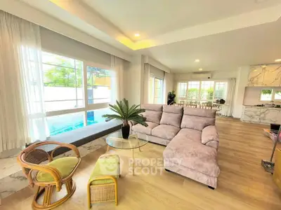 Spacious living room with modern decor and pool view, featuring a cozy sectional sofa and elegant furnishings.