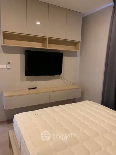 Modern bedroom with wall-mounted TV and sleek storage cabinets