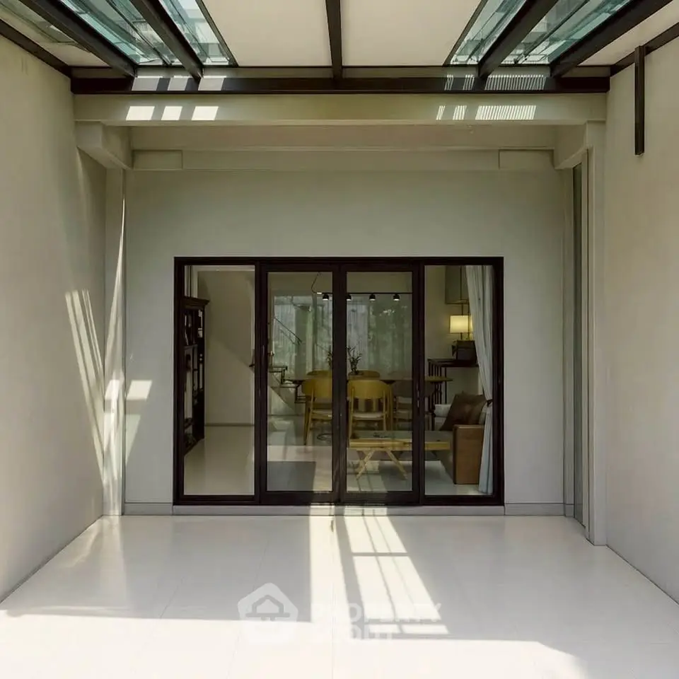 Modern home with glass doors leading to a spacious living area, featuring sleek design and ample natural light.