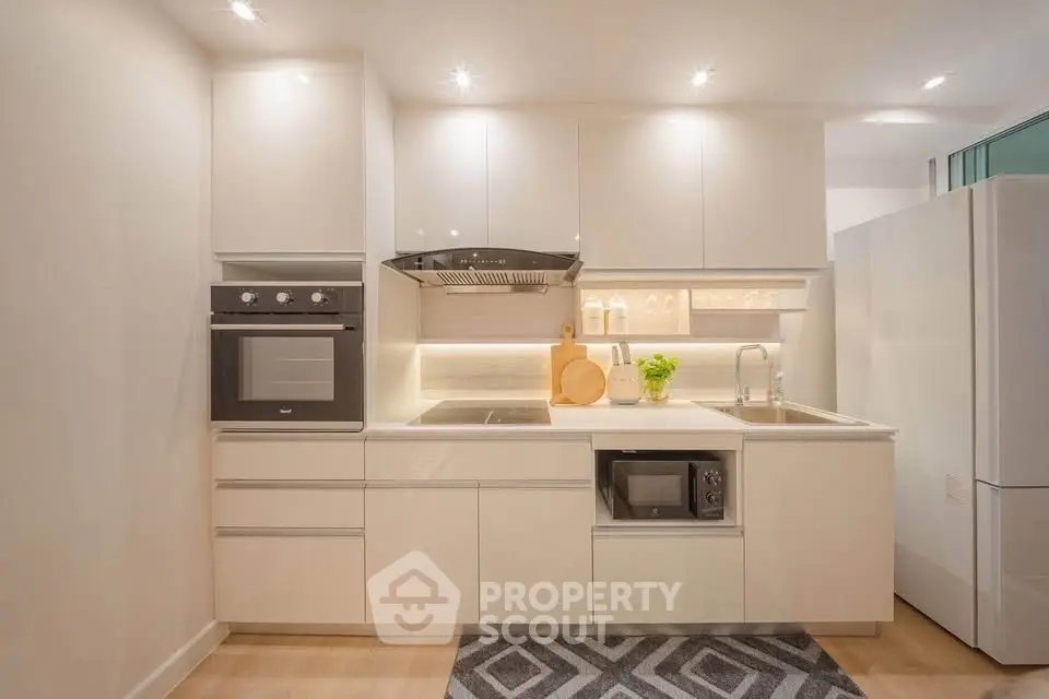 Modern kitchen with sleek white cabinetry, built-in oven, and microwave, perfect for contemporary living.