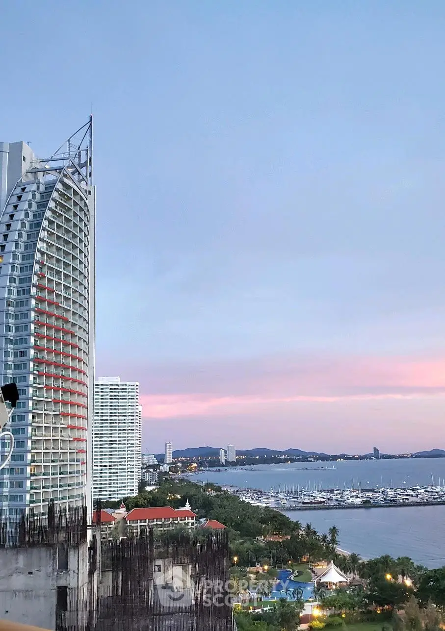 Stunning coastal view with modern high-rise building and marina at sunset, perfect for luxury living.