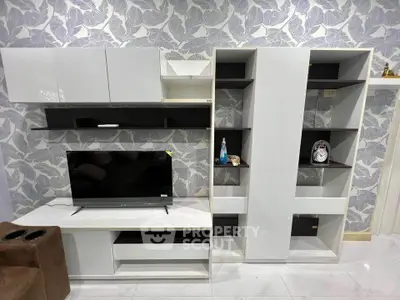 Modern living room with sleek white entertainment center and stylish wallpaper.