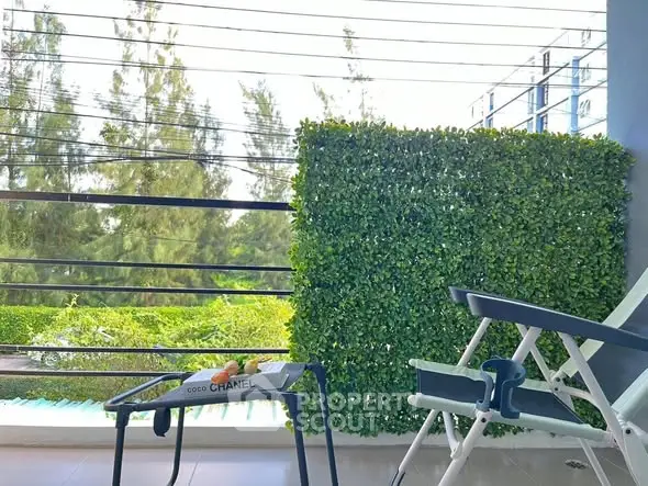 Charming balcony with lush greenery and cozy seating area, perfect for relaxation.