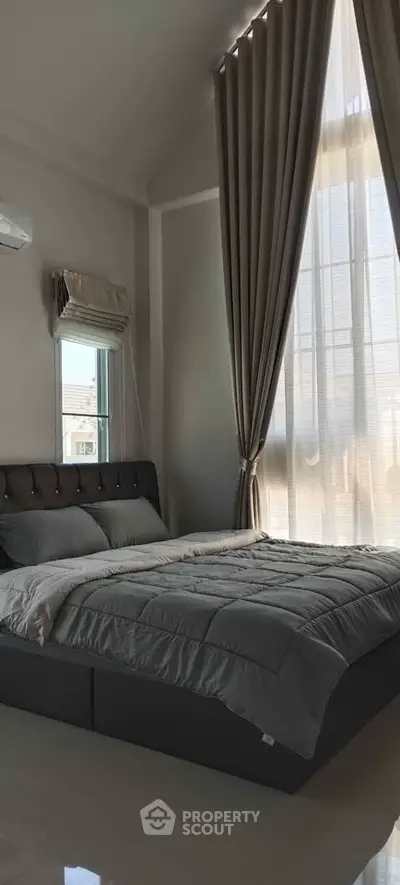 Luxurious bedroom with high ceilings and elegant curtains, perfect for relaxation and comfort.