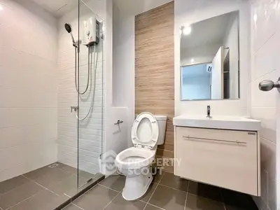 Modern bathroom with glass shower, sleek vanity, and neutral tiles.
