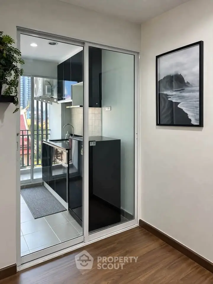 Modern kitchen with sleek black cabinets and balcony view in stylish apartment.