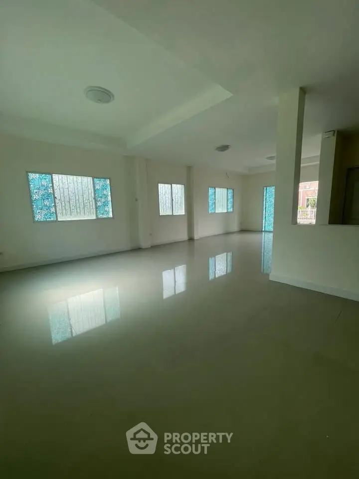 Spacious empty room with large windows and glossy tiled floors, ideal for customization.