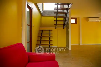 Modern interior with vibrant yellow walls and stylish staircase, featuring a bold red sofa for a pop of color.