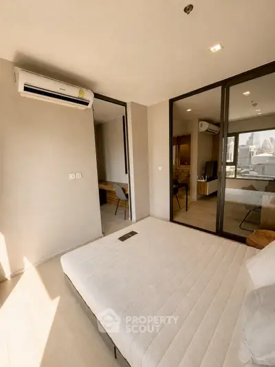 Modern bedroom with large windows and city view, featuring minimalist decor and air conditioning.