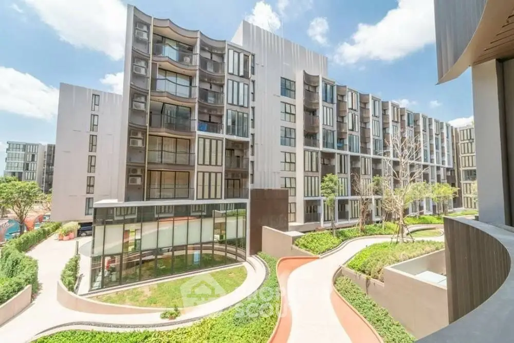 Modern apartment building with lush landscaping and unique architectural design.