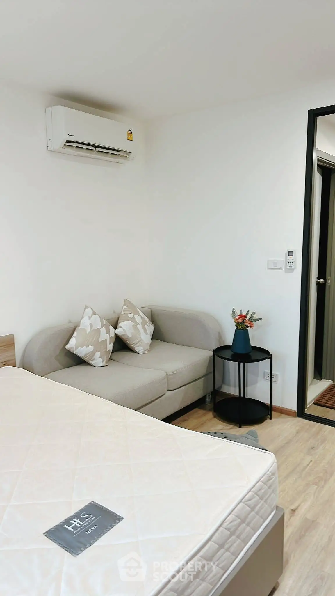Cozy bedroom with modern decor and air conditioning, featuring a comfortable sofa and stylish side table.