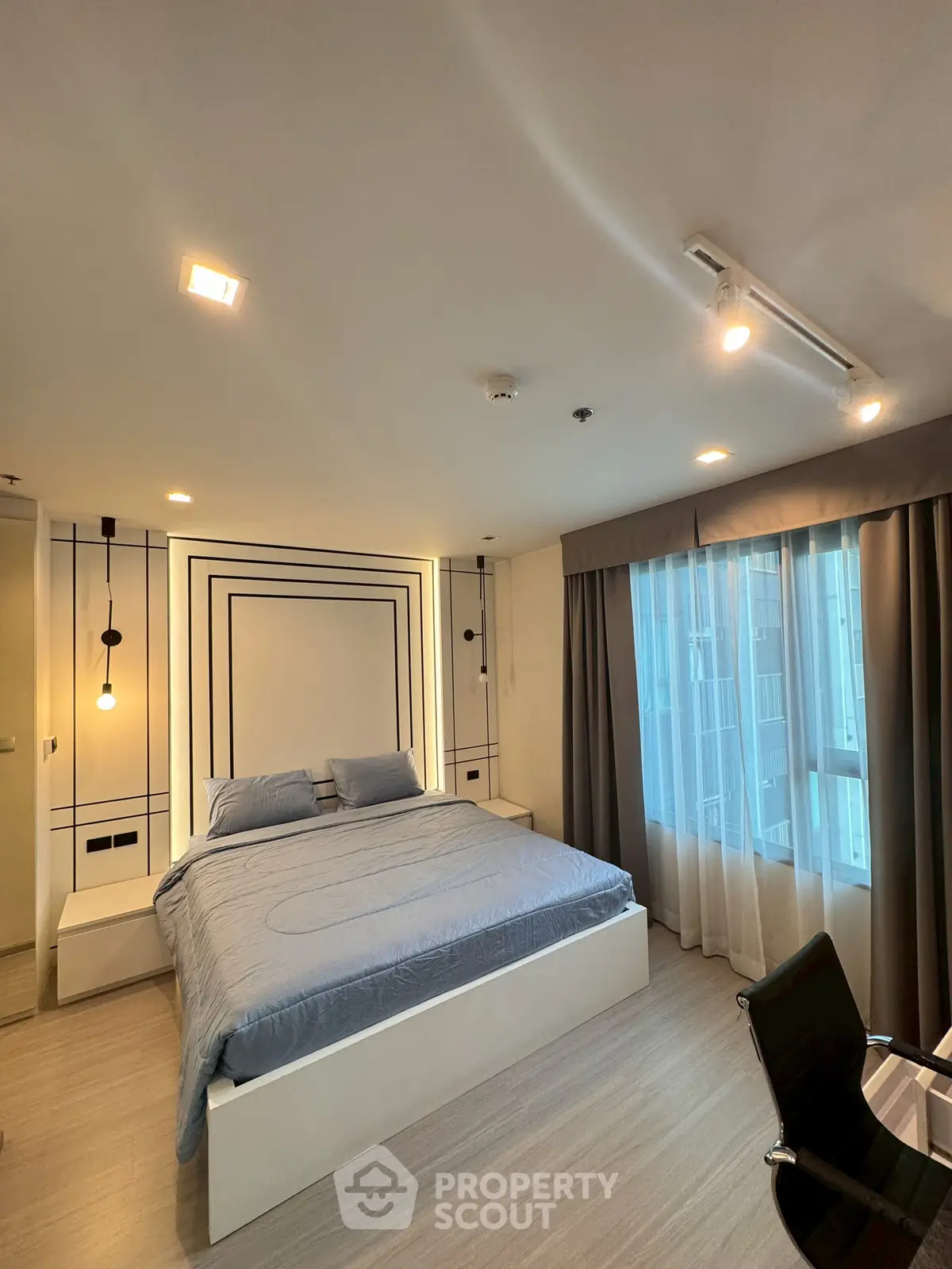 Modern bedroom with stylish decor and large window in a contemporary apartment.