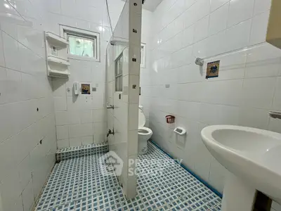 Spacious bathroom with modern fixtures and tiled flooring in a bright, airy setting.