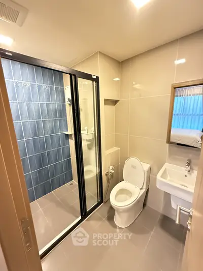 Modern bathroom with glass shower and sleek fixtures in contemporary apartment.