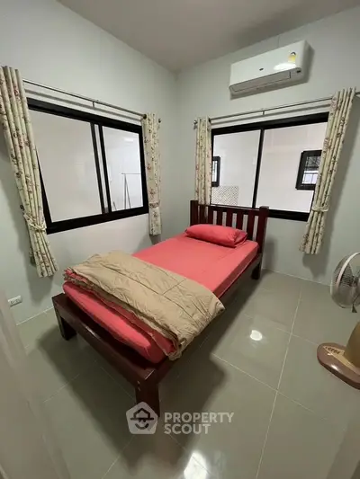 Cozy bedroom with single bed, air conditioning, and large windows for natural light.