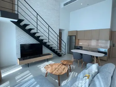 Modern loft-style living room with open kitchen and sleek staircase