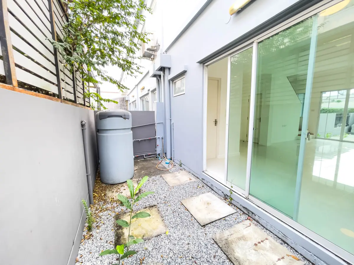 Modern exterior view of a sleek building with glass doors and a small outdoor area.