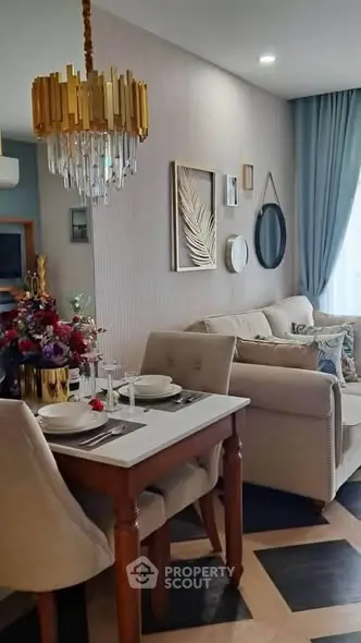 Elegant living room with stylish decor and dining area, featuring a luxurious chandelier and cozy seating.