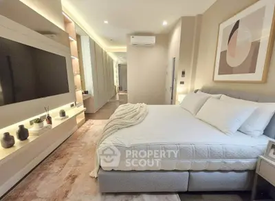Luxurious modern bedroom with elegant decor and large TV, perfect for relaxation and comfort.