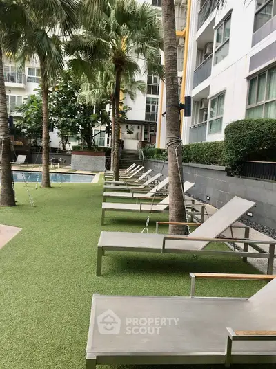 Luxurious poolside area with modern lounge chairs and lush greenery in a high-end residential complex.