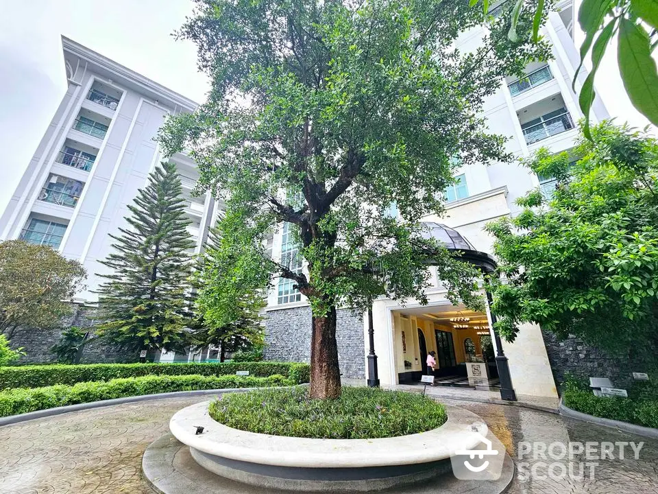 Elegant building entrance with lush greenery and circular driveway