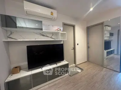 Modern living room with sleek TV unit and air conditioning, featuring stylish decor and wood flooring.
