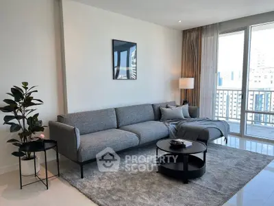 Modern living room with sleek gray sofa, stylish decor, and large windows offering city views.